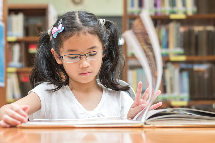 A young girl reads a book at the library