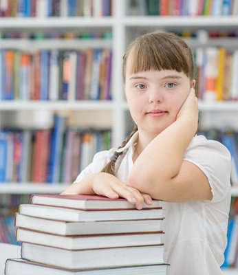 Young autistic girl with a stack of library books.
