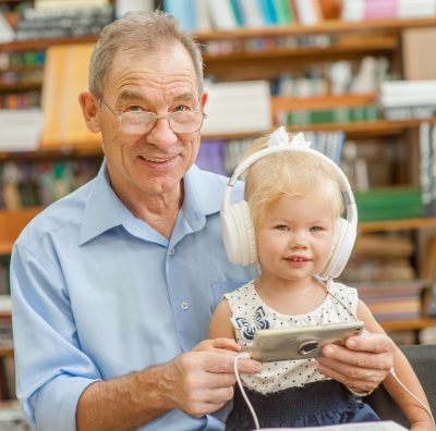 A grandfather reads to his toddler granddaughter.