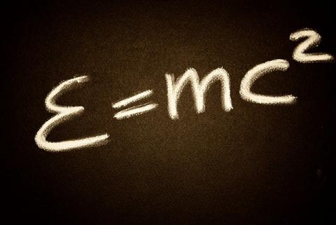 Einstien's E=mc2 equation written on a chalk board