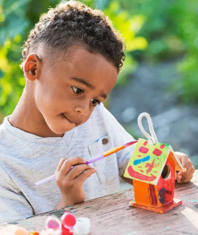 Young boy painting a birdhouse.