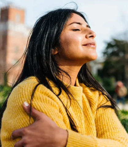 Teen girl in yellow sweater hugs herself