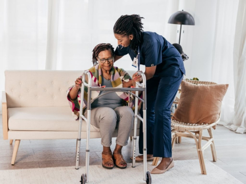 A woman assists another woman who is in a wheelchair.