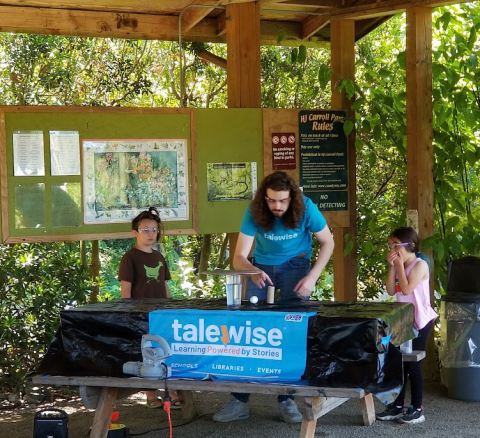 Two kids and an adult around a picnic table doing a science experiment