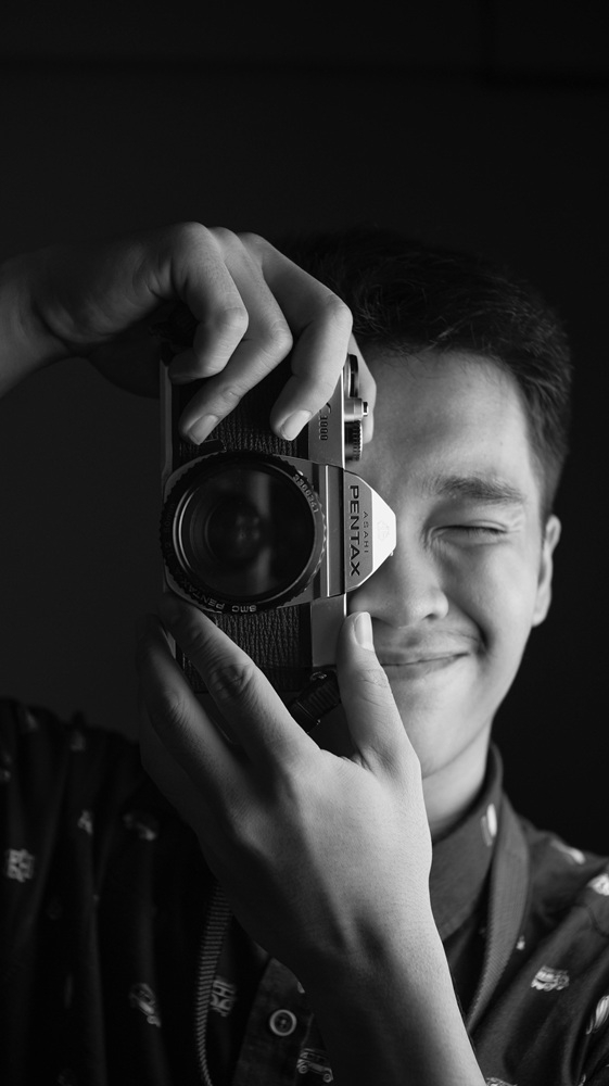 Black and white photo of a teen with a camera.