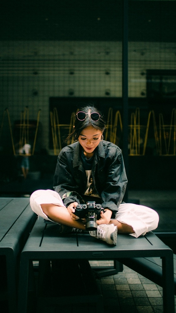 Woman Sitting Down Looking Into a Camera Lens
