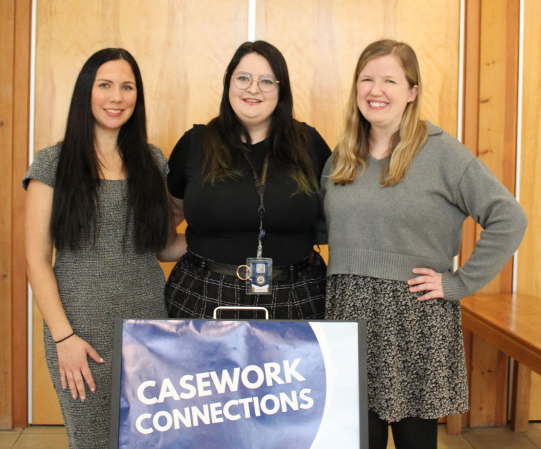 Three women standing together holding a box labled Casework Connections
