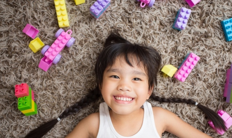 Cute girl surrounded by LEGO bricks.