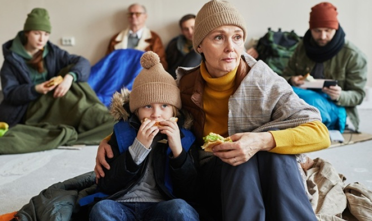 Woman and child sharing a sandwich in a shelter after a disaster.