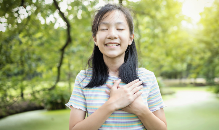 Teen girl showing love for herself with her hands over her heart.